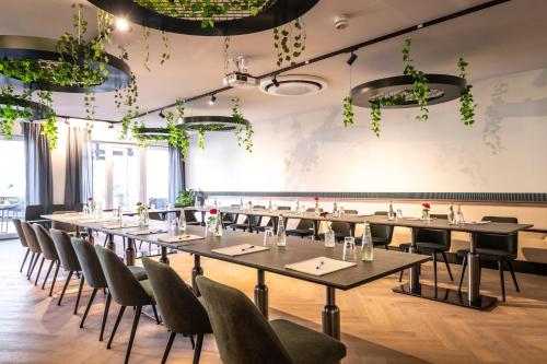 a row of tables and chairs in a room with plants at May Hotel Mayschoß in Mayschoß