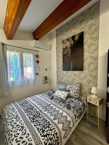 a bedroom with a black and white comforter on a bed at Le jardin secret in Uchaud