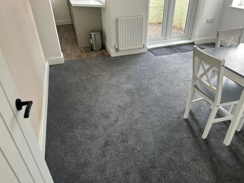an empty living room with a table and a chair at 3 Double Bedroom Home-Sleeps 8 - Castle Donnington in Castle Donington