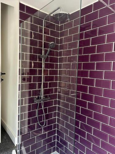 a purple tiled shower with a shower head in a bathroom at 3 Double Bedroom Home-Sleeps 8 - Castle Donnington in Castle Donington