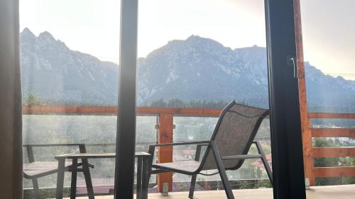 a chair and table on a balcony with a view of the mountains at Busteniview in Buşteni