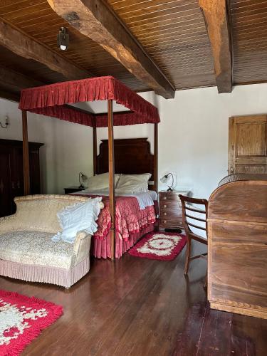 a bedroom with a canopy bed and a chair at Casa da Eira in Cabeceiras de Basto