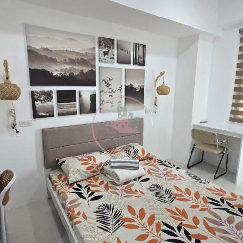 碧瑶Stanford 6F19 Baguio Condo by Dei Gratia的一间卧室配有一张床和一张书桌,墙上挂有图片