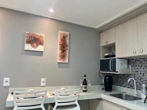 a kitchen with a sink and a counter with chairs at Blue Sunset com Varanda - Experience in João Pessoa
