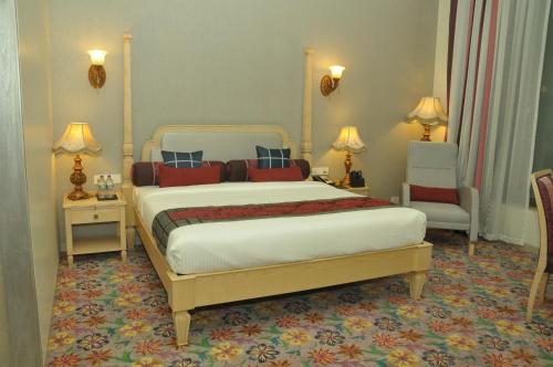 a bedroom with a large bed and two chairs at Royal Tulip Navi Mumbai in Navi Mumbai