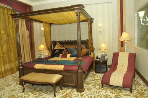 a bedroom with a canopy bed and a chair at Royal Tulip Navi Mumbai in Navi Mumbai