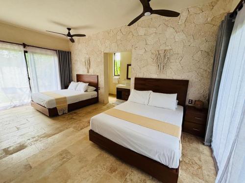 a bedroom with two beds and a stone wall at Nalhá Hotel Boutique y Villas in Bacalar