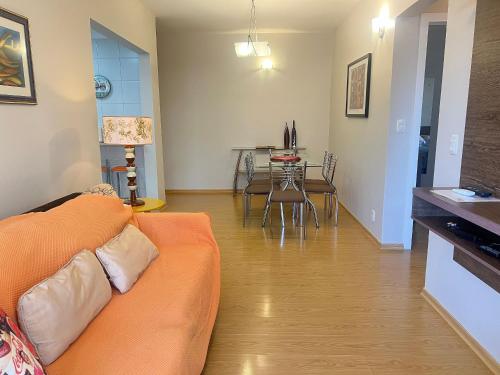 a living room with an orange couch and a table at Apto centro 50m Via del Vino in Bento Gonçalves