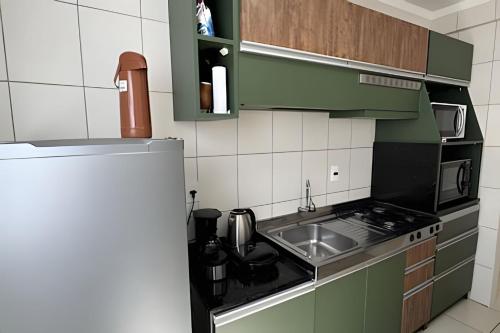 a small kitchen with a sink and a refrigerator at Residencial Astrogildo - Perto de TUDO! LZN Hospedagens in Santa Maria