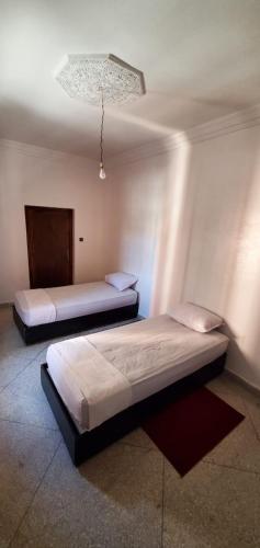 two beds in a room with a chandelier at Appartement City Center in Ouarzazate