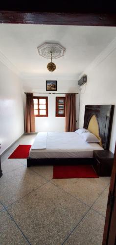 a bedroom with a large bed with a red rug at Appartement City Center in Ouarzazate