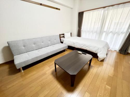 a living room with a couch and a bed and a table at Blue Eyes Chuo - Vacation STAY 16693 in Kagoshima