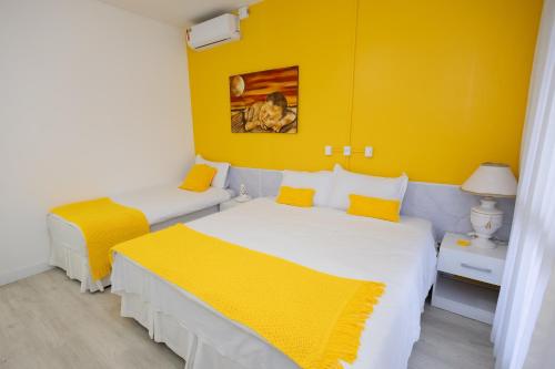a bedroom with two beds and a yellow wall at Pousada Buona Serata in Bento Gonçalves