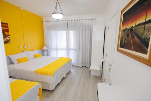 a bedroom with a bed and a yellow wall at Pousada Buona Serata in Bento Gonçalves