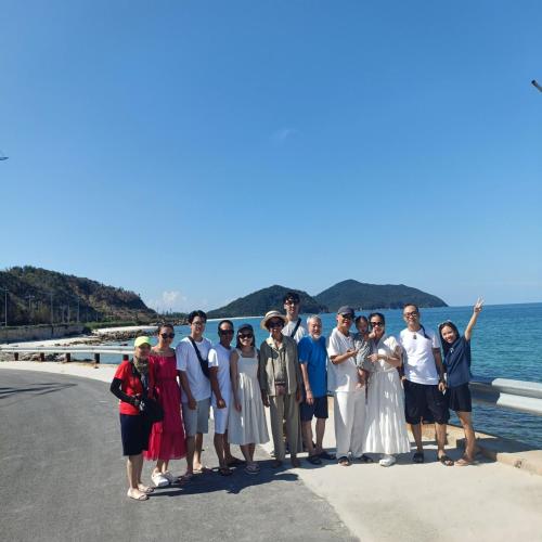 a group of people posing for a picture next to the ocean at Quan Lan Nam Phong Hotel in Quan Lạn