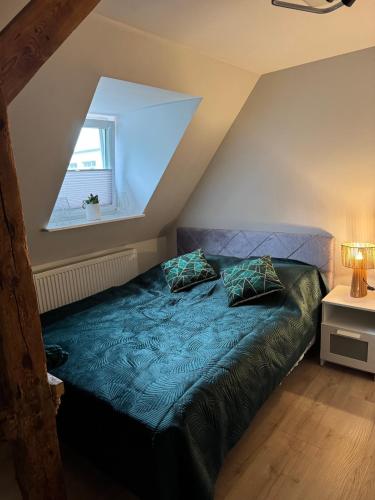 a bed with two pillows in a attic room at Apartamenty przy parku in Elblag