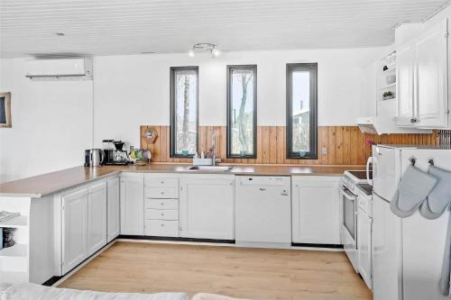 a white kitchen with white appliances and windows at M157-Stubbekobing-Tjornehegnet-27 in Stubbekøbing