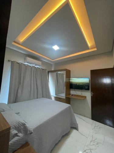 a bedroom with a large bed and a television at Casa Solar Beach in Vilhena