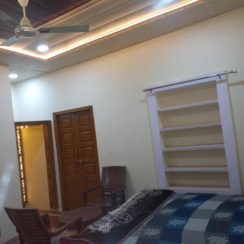 a bedroom with a bed and chairs and a ceiling fan at VENU NAAD BHAWAN Yatri Niwas in Mathura