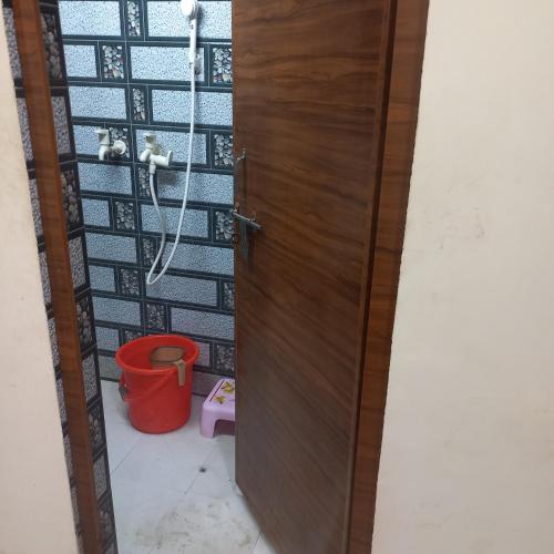 a bathroom with a wooden door and a bucket at VENU NAAD BHAWAN Yatri Niwas in Mathura