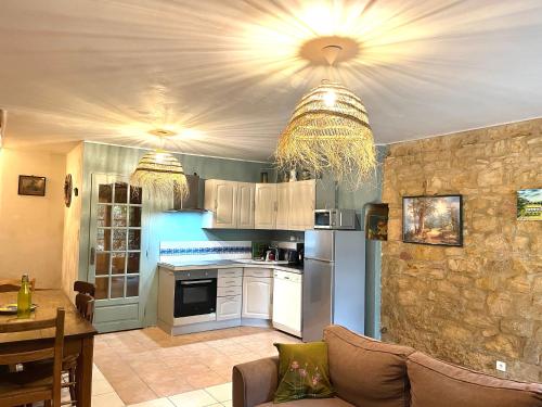 cocina con electrodomésticos blancos y mesa con sofá en La Riviere Esperance, en Veyrignac