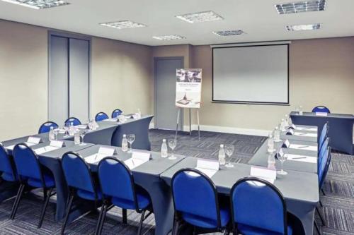 a conference room with tables and blue chairs and a screen at Lindo FLAT SP Jardins Ibirapuera com vaga inclusa in Sao Paulo