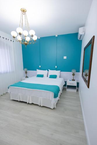 a blue bedroom with a large bed and a chandelier at Pousada Buona Serata in Bento Gonçalves
