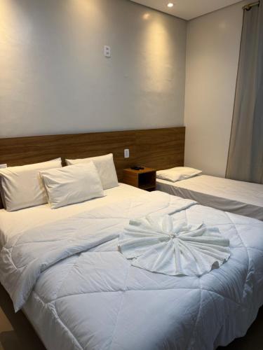 a hotel room with two beds with white sheets at Hotel Mapuera in Oriximiná