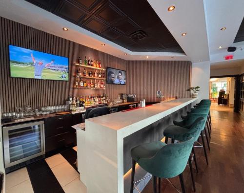 a bar with green chairs and a television on the wall at Hôtels Gouverneur Trois-Rivières in Trois-Rivières