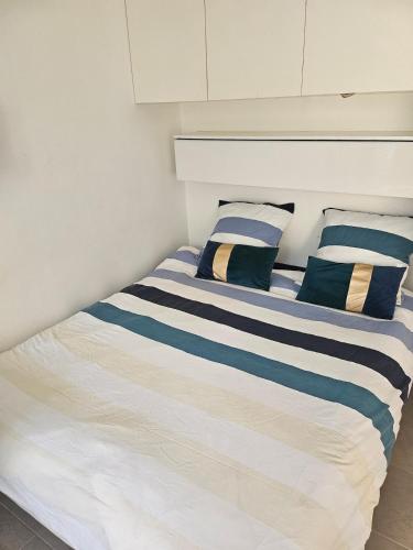 a bed with blue and white striped sheets and pillows at Studio calme à mantes la ville in Mantes-la-Ville