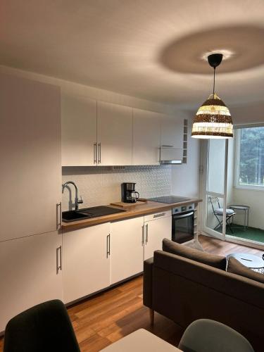 a kitchen with white cabinets and a couch in a room at Spacious 4 bedroom family home 5 min from Caen in Hérouville-Saint-Clair