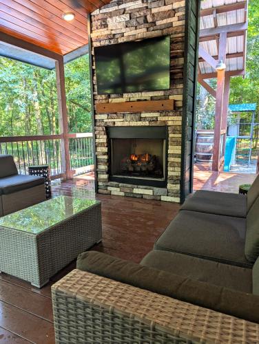 a screened in porch with a fireplace with a tv at Wine Time 5 Bedroom Shuffleboard Hot Tub Fire Pit Play Set in Broken Bow