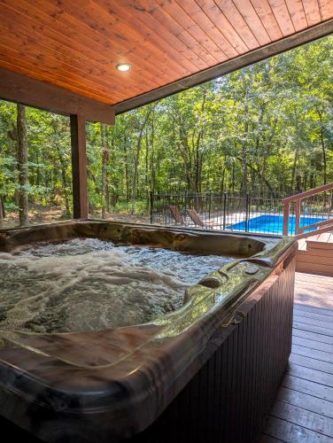 a hot tub on the deck of a house at Wine Time 5 Bedroom Shuffleboard Hot Tub Fire Pit Play Set in Broken Bow