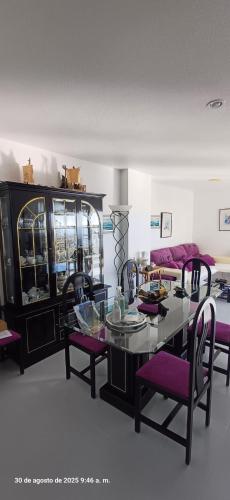 a dining room with a glass table and purple chairs at Residencial Aguilas Playa in Águilas