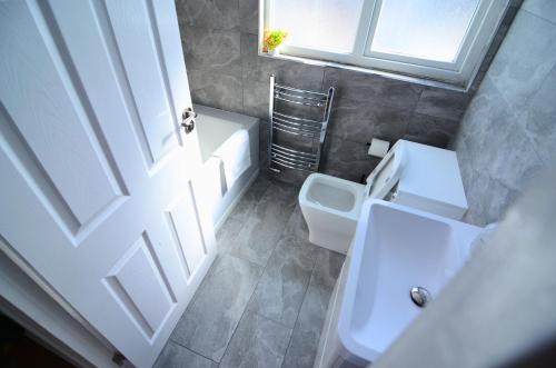 a bathroom with a toilet and a sink and a window at Hertfordshire - Stylish 6BR Retreat, 3 Parking in Stevenage