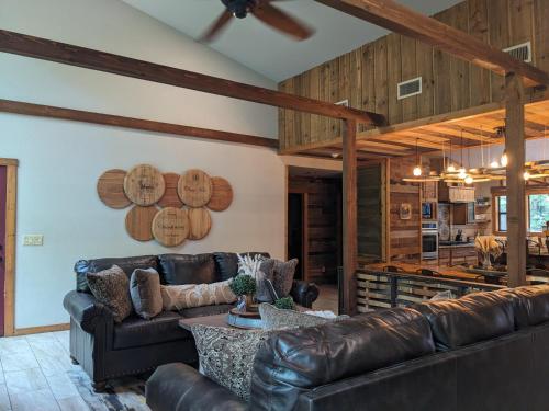 a living room with leather couches and a kitchen at Wine Time 5 Bedroom Shuffleboard Hot Tub Fire Pit Play Set in Broken Bow