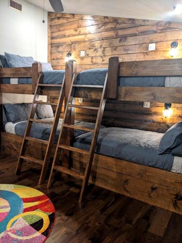 two bunk beds in a room with wooden walls at Wine Time 5 Bedroom Shuffleboard Hot Tub Fire Pit Play Set in Broken Bow