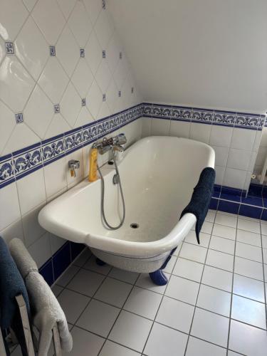 e bagno con vasca e piastrelle bianche e blu. di Le Char'Mans, cocon suréquipé en centre ville a Le Mans