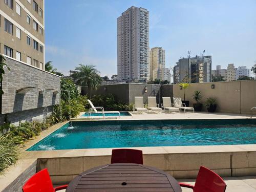 - une piscine avec une table et des chaises dans l'établissement Studio Charmoso 2km do Aeroporto de Congonhas, à São Paulo