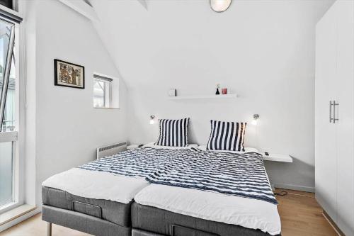 a white bedroom with a large bed with striped pillows at M318-Vaeggerlose-Marielyst-Strandvej-63-S in Marielyst