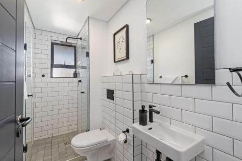 a white bathroom with a toilet and a sink at Lira On White Soil in Cape Town