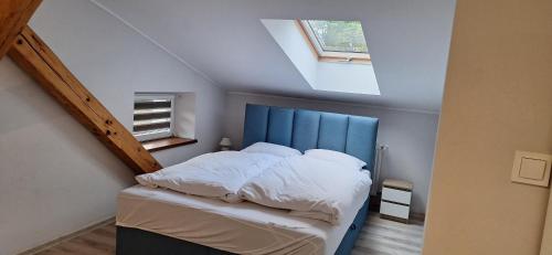 a bedroom with a bed with a blue headboard and a window at Apartamenty "Kotlina" in Bystrzyca Kłodzka