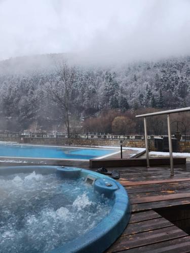 a hot tub on a deck with a snow covered mountain at Студио Бети Балнео Спа Хотел Свети Спас in Velingrad