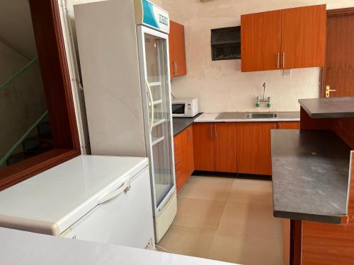 a white refrigerator in a kitchen with wooden cabinets at Sadili Oval B & B in Nairobi