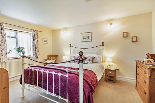 una camera da letto con un grande letto con coperta viola di The White Horse Cottage a Saint James