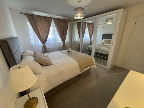 ein Schlafzimmer mit einem großen Bett und einem Spiegel in der Unterkunft Modern House with Garden and Parking in Cardiff