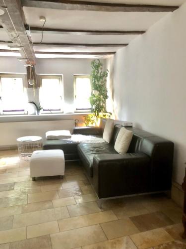 a black leather couch in a living room with windows at Moderne Fachwerk-Wohnung im Herzen von Herborn in Herborn