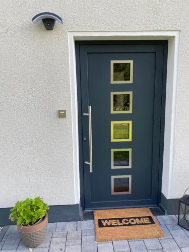 a blue door with a welcome mat in front of it at Kleines WaldGlück Wennemen in Meschede