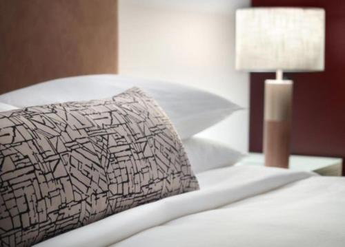 a white bed with a pillow and a lamp at Omni Viking Lakes in Eagan