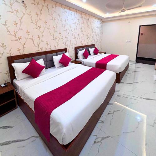 two beds in a hotel room with red pillows at Hotel Om Palace in Mathura